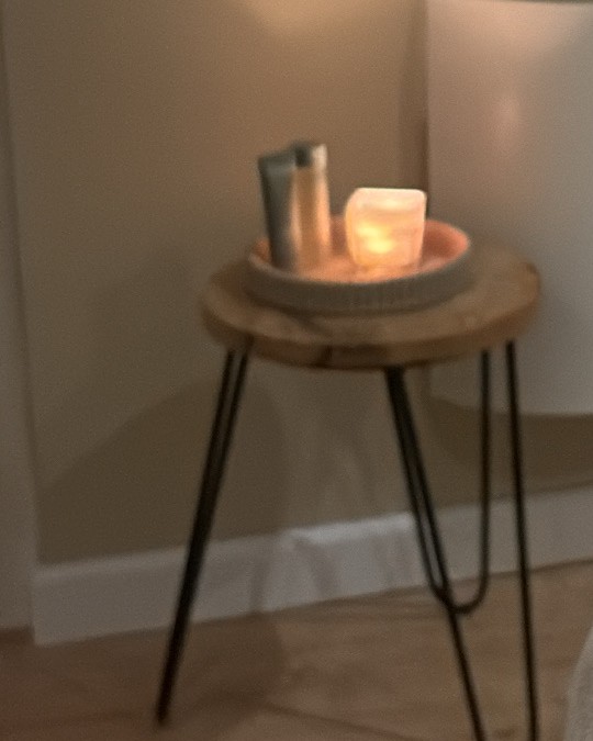 Een brandende kaars op een houten krukje in de behandelruimte